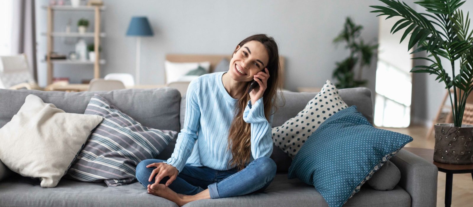Attractive smiling woman talking on the phone at home. Technology, communication and coziness concept.